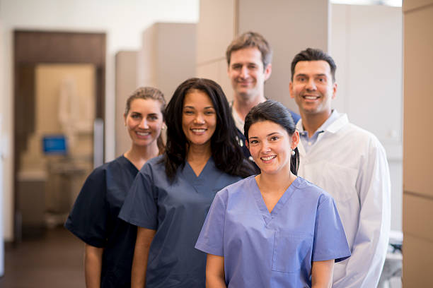 A group of doctors, nurses, and or dentists and professional assistants posing for a picture in a medical clinic.