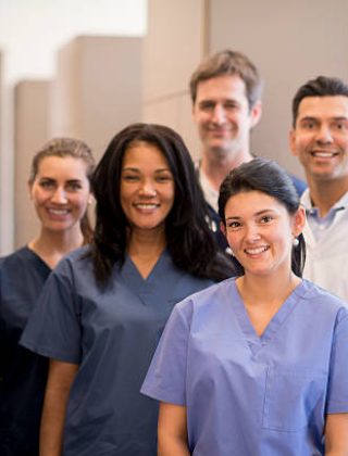A group of doctors, nurses, and or dentists and professional assistants posing for a picture in a medical clinic.