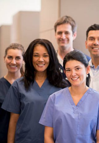 A group of doctors, nurses, and or dentists and professional assistants posing for a picture in a medical clinic.